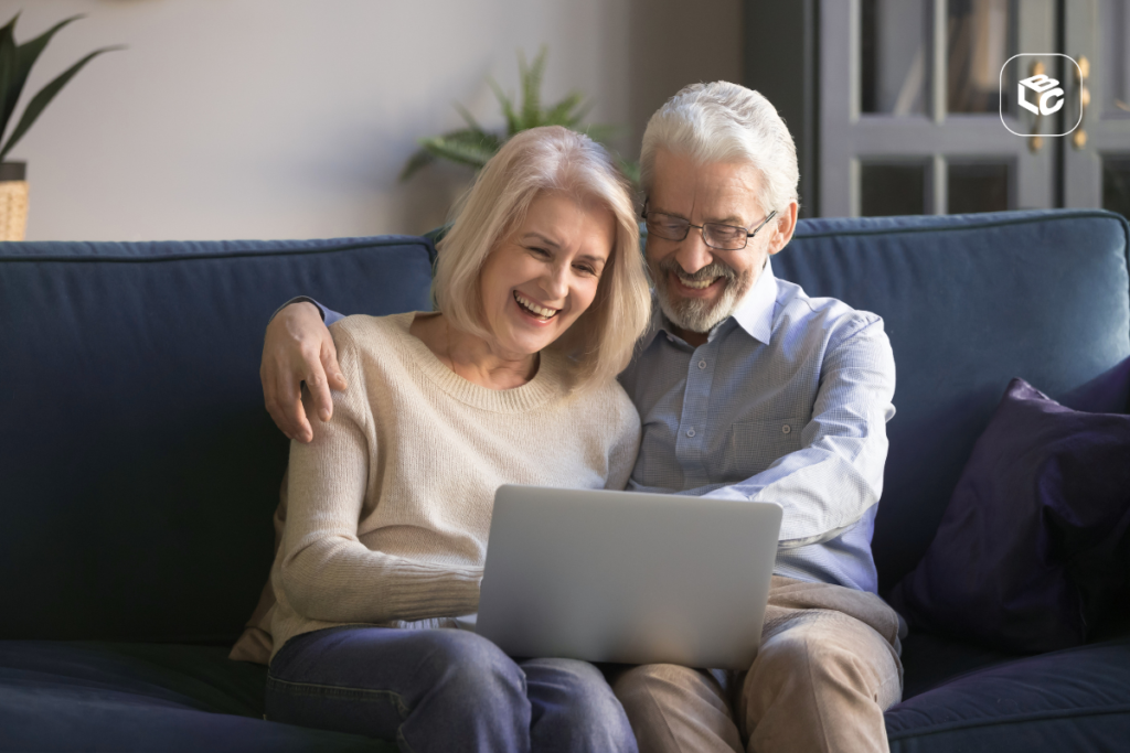 Casal sênior sorri assistindo laptop, protegendo direitos previdenciários